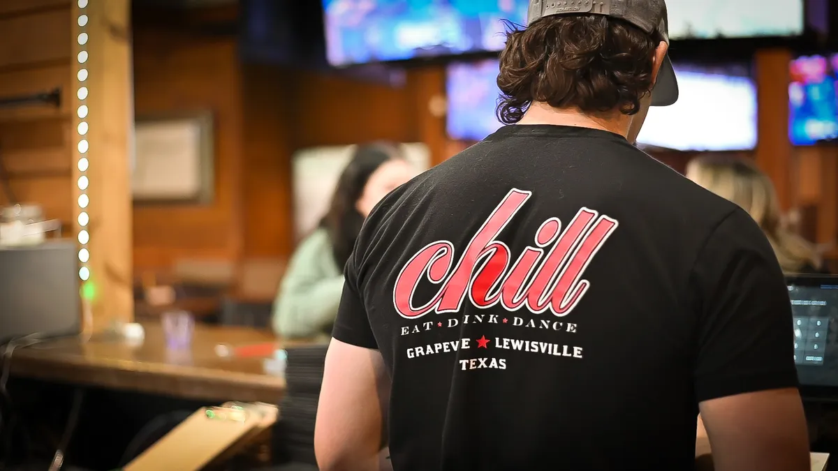 Staff inside the sports bar wearing the branded Eat · Drink · Dance T-shirt at Chill Bar & Grill in Lewisville, TX